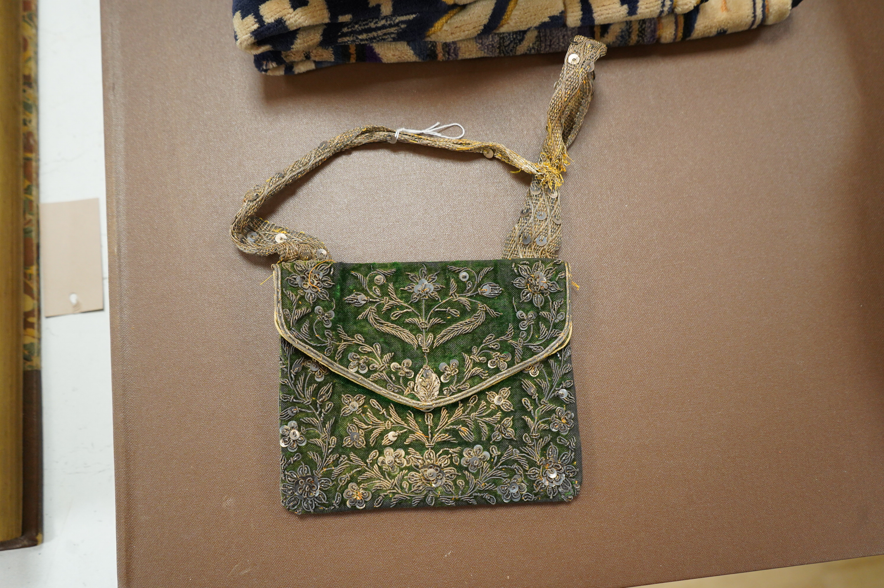 A collection of 20th century textiles to include: child's cream and gold embroidered waistcoat, a metallic embroidered bag, a leather embroidered bag, two Art Deco printed velvet cushion covers, a cotton quilted runner a